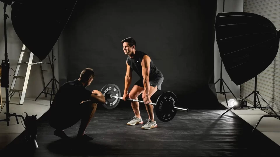 Admedia behind the scenes at a studio photoshoot, capturing a man lifting weights, showcasing content creation services for effective marketing work.