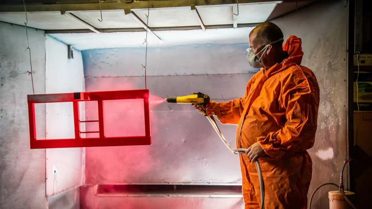 Admedia photography capturing the K Care manufacturing process: a worker powder coating a medical equipment component, highlighting Australian-made quality.