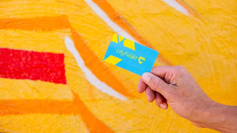 A hand holding a Mildura City Heart gift card in front of a mural