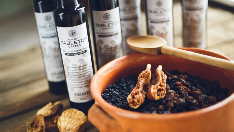 Tabletop Grapes dried fruit served in terracotta bowl with walnuts and Tabletop Grapes wine bottles in background
